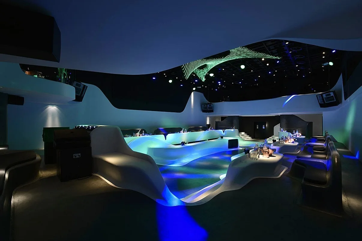 Blue floor lighting through the lounge with the sculpture in green above and a starfield of ceiling points