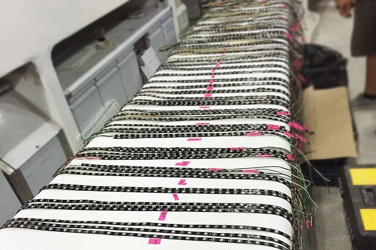Close up of black pixel tape runs laid out side by side and marked with pink tape before soldering