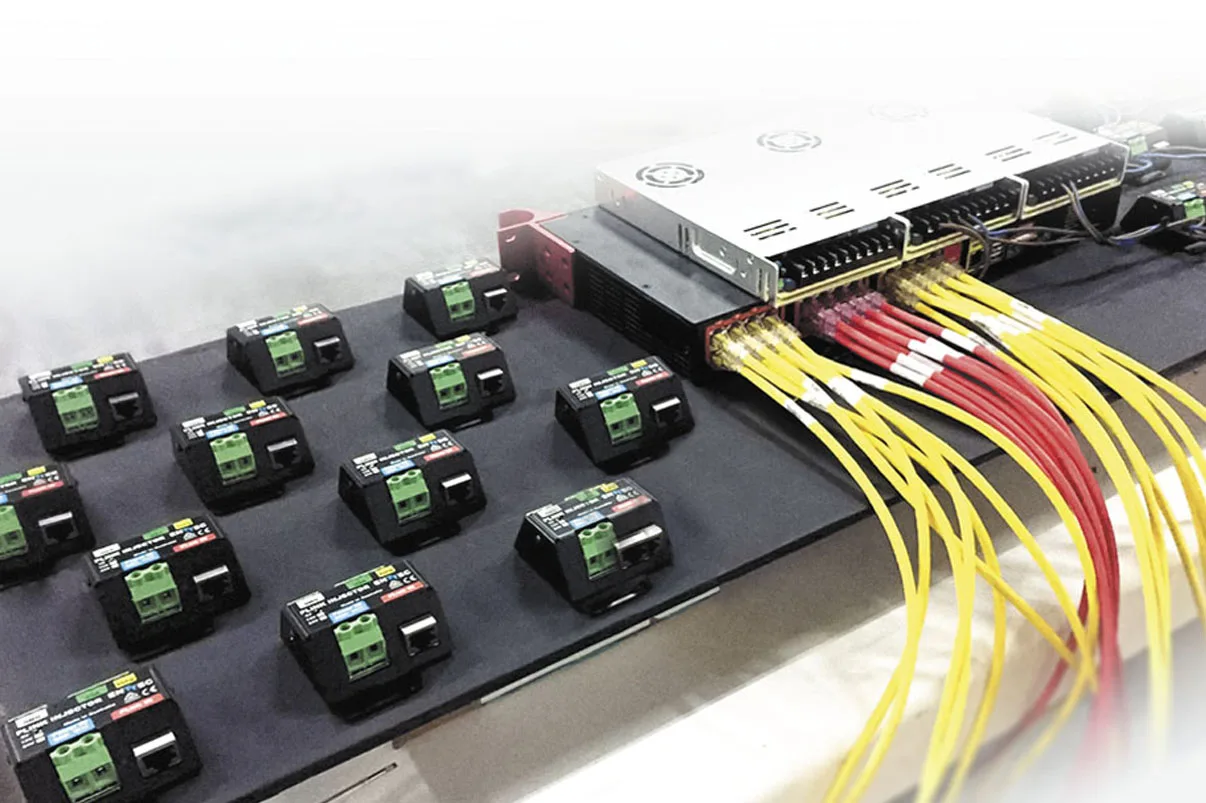 Rows of PLink injectors laid out on a bench, yellow data leads and red power cable running back to a metal supply
