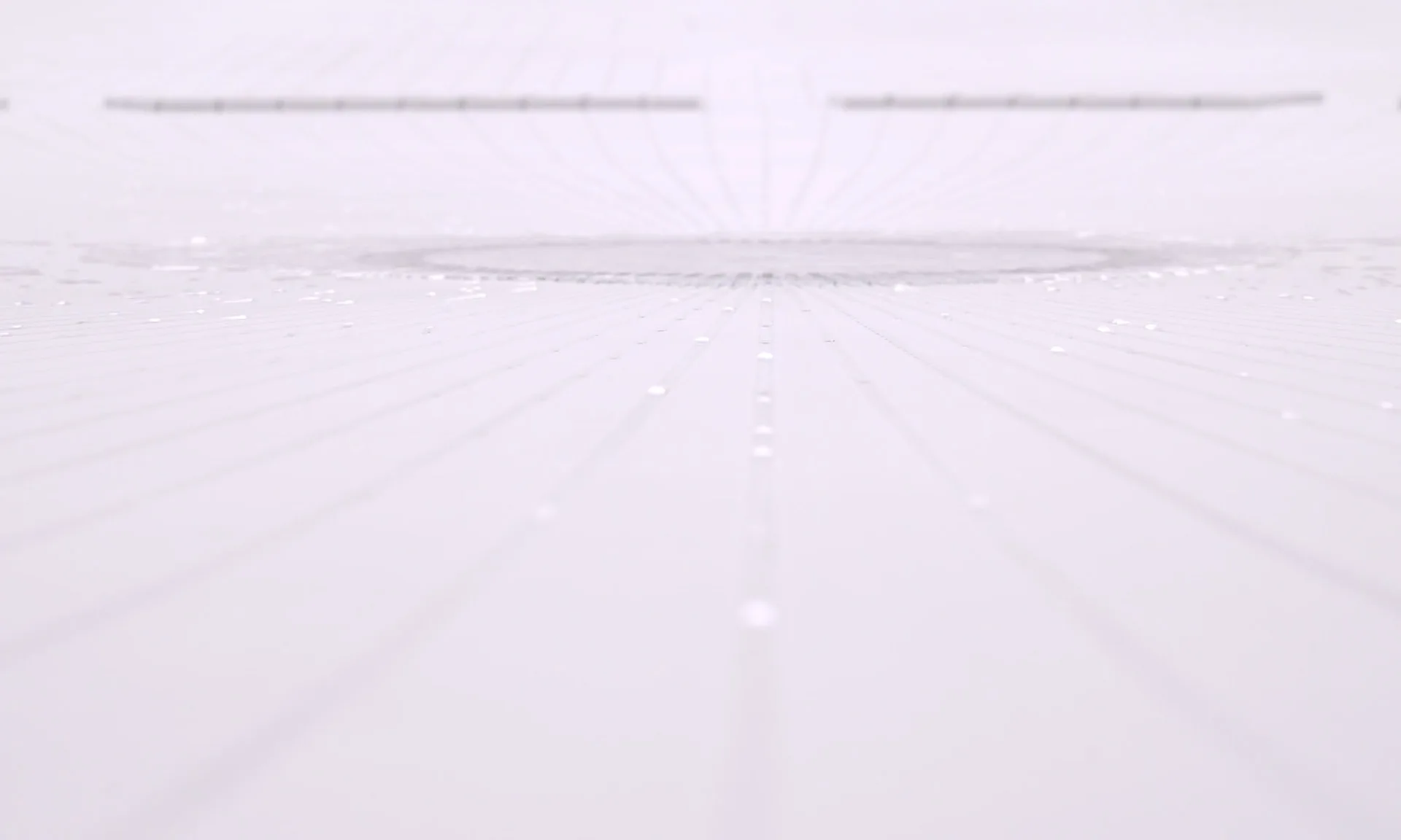 Low view across the white surface toward the circular basin, faint trails of droplets converging on it