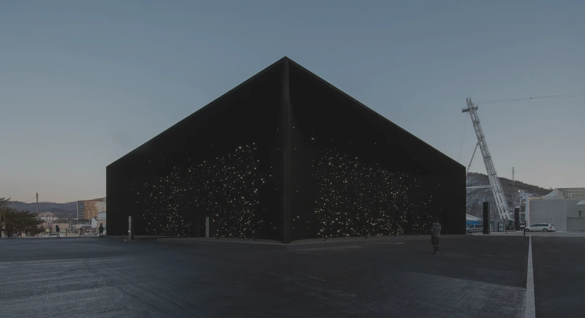 The Hyundai Pavilion at dusk, its black outer walls scattered with thousands of white points of light across the empty forecourt