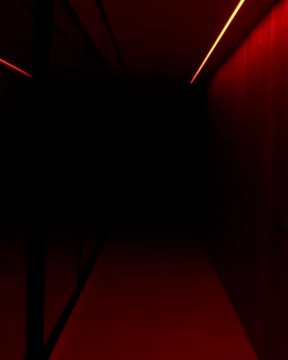 The corridor at its darkest, faint red on the walls and a thin amber line running along the ceiling